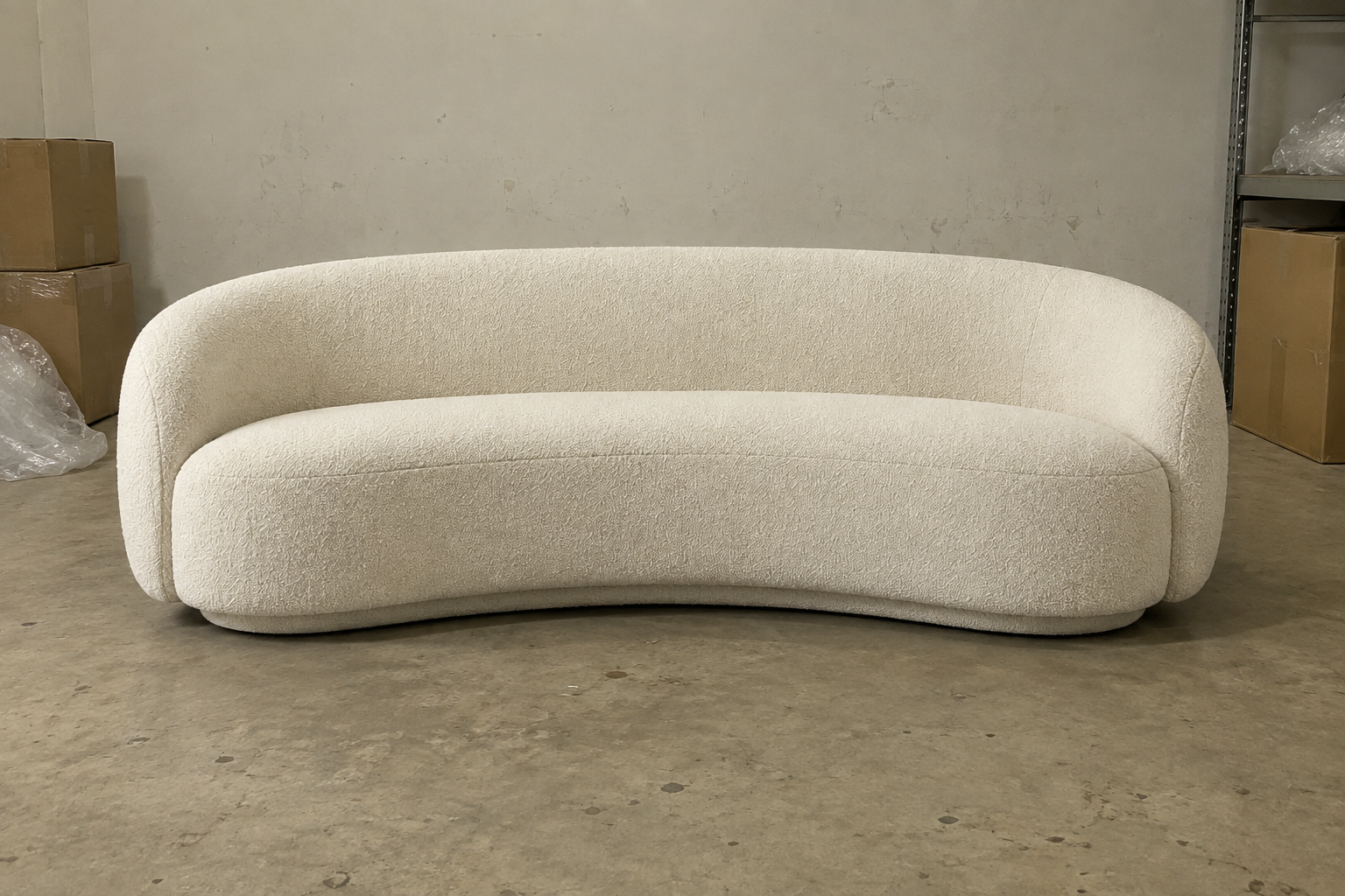 Illustrative curved cream sofa poorly lit stockroom snapshot